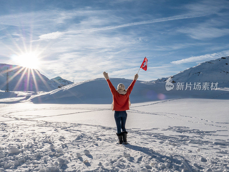 举着瑞士国旗站在瑞士阿尔卑斯山白雪皑皑的山上的女子