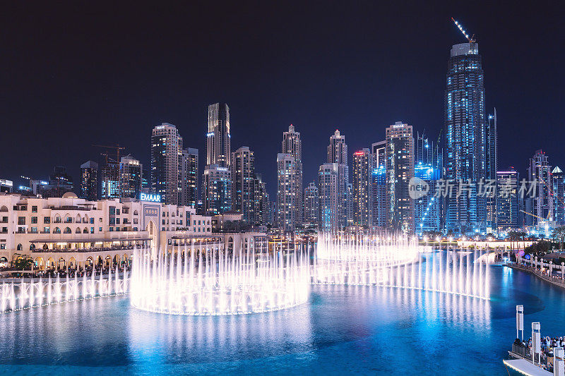 晚上，在哈利法塔和迪拜购物中心附近的游泳池里，喷泉在跳舞