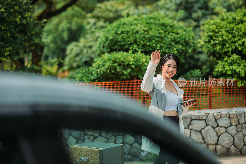 亚洲华人少女在街上用手拿着智能手机叫车