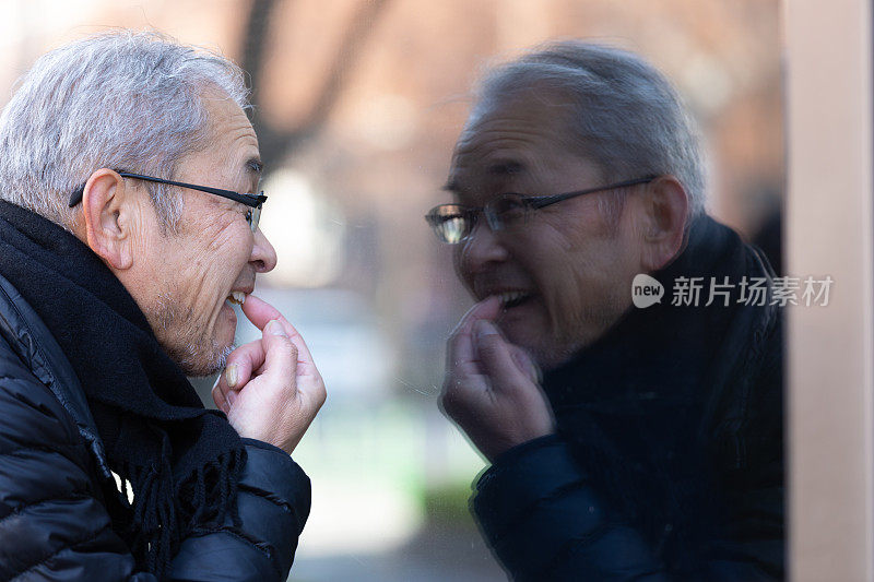 老男人在窗前的倒影中看着自己