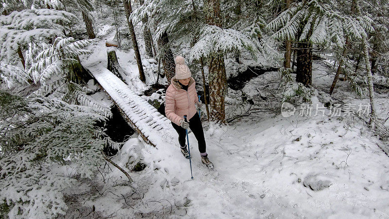 女性徒步旅行者在一条被雪覆盖的小径上行走