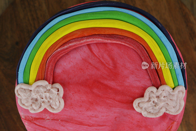 自制彩虹蛋糕的图像，巧克力海绵抹上黄油奶油糖霜，装饰着方旦糖糖霜彩虹和云彩，俯瞰