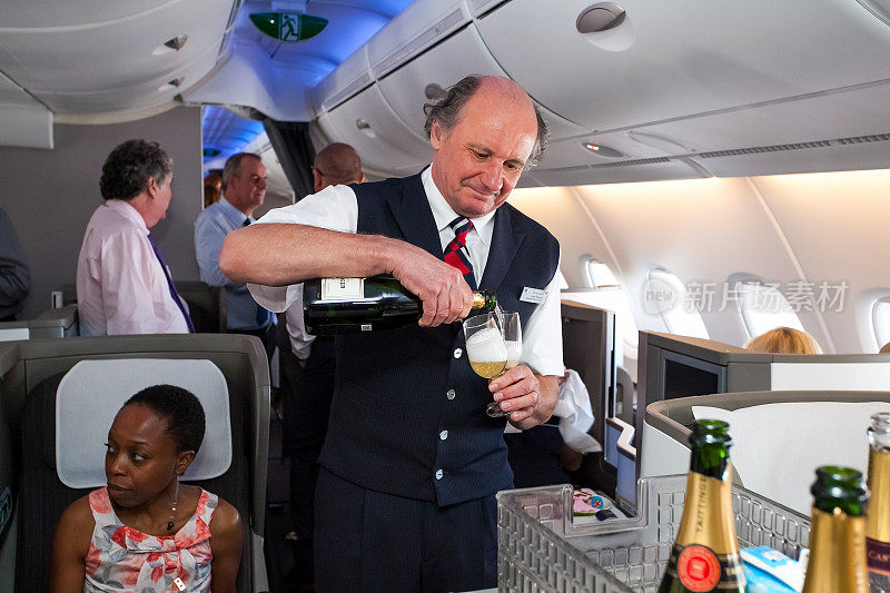 一架空客A380商务舱的男机组人员正在倒一杯香槟