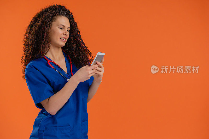 年轻女医生，带着智能手机，橙色背景