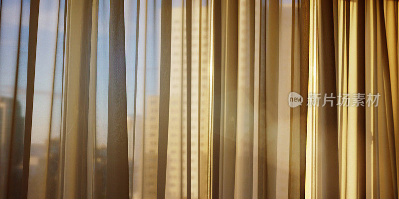 傍晚透过透明窗帘照射在家里或办公室窗户上的阳光