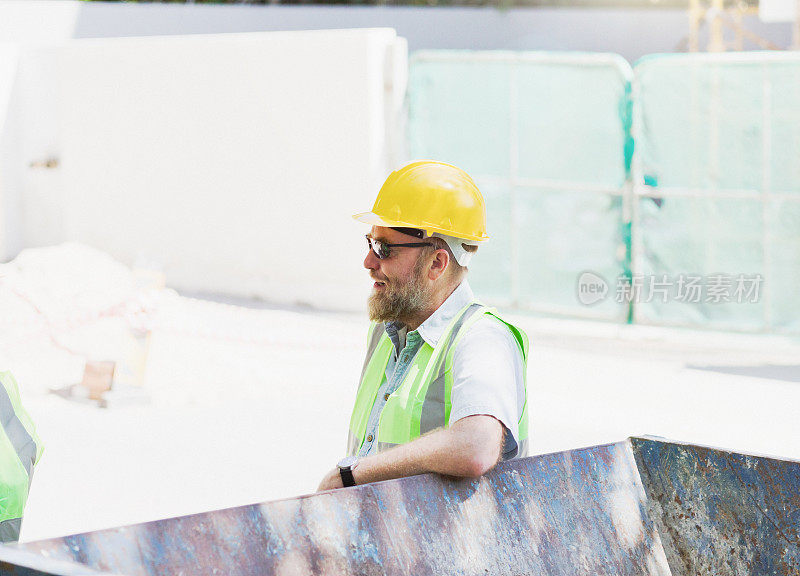 建筑工人在建筑工地休息时，把胳膊肘搁在垃圾桶上