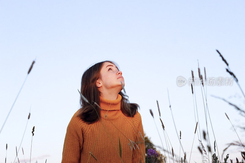 可爱的女孩望着天空走在田野里