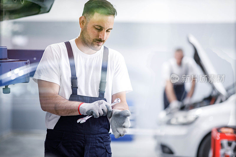 一个年轻的汽车修理工正在车间里准备他的工作。