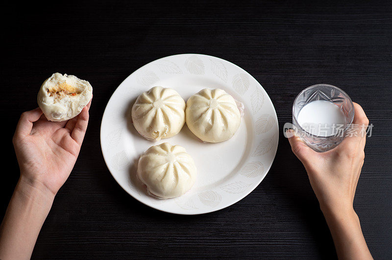 妇女在家里吃包子和牛奶馒头的早餐