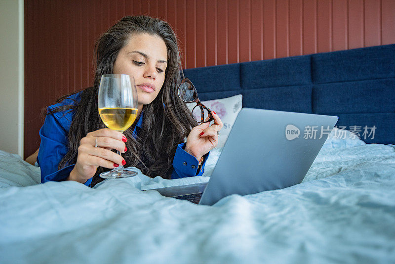 辛苦工作一天后，在卧室里喝一杯白葡萄酒，读读电子邮件。