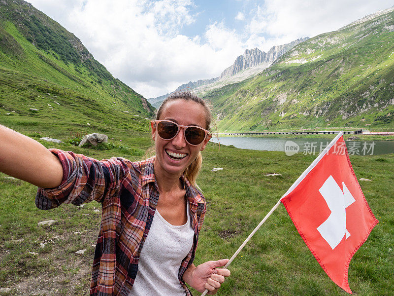 一名年轻女子在山顶用瑞士国旗自拍