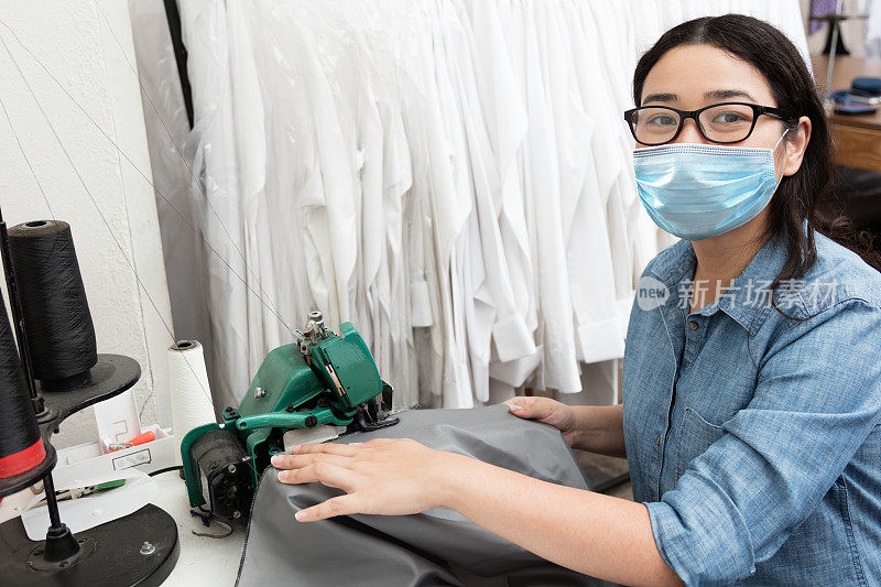 一个女裁缝企业家戴着保护面罩在她的工作室缝纫的肖像