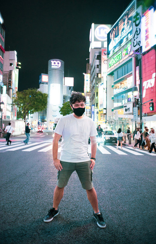 一幅戴着面具的亚洲男子的肖像，展示着城市的夜景