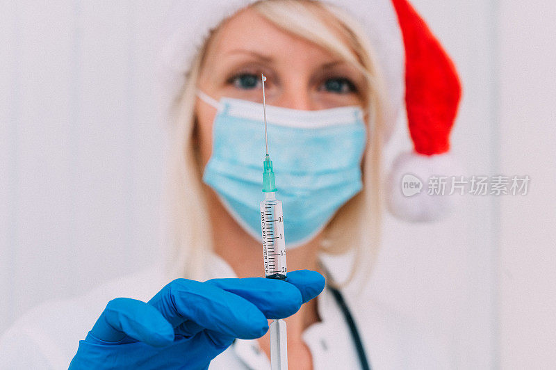 一个年轻的女医生在圣诞帽拿着注射器的特写
