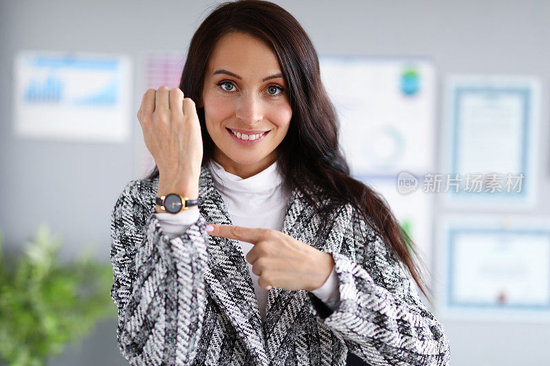 美丽的女人用钟表把手指放在手上。