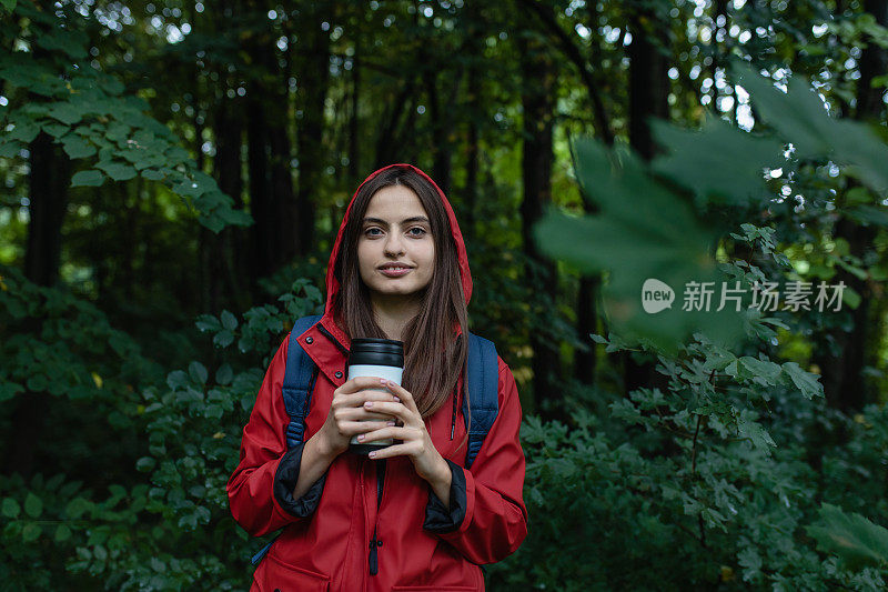 穿着红色雨衣的年轻女子在大自然中徒步旅行