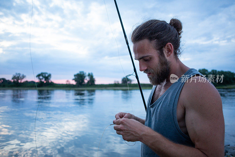 黄昏时分，一个人拿着钓竿站在河边