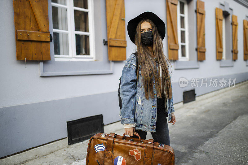 年轻女子在冠状病毒大流行期间携带复古行李箱旅行