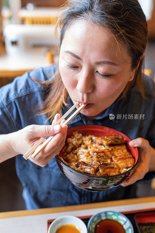 一个日本女人吃鳗鱼饭的特写