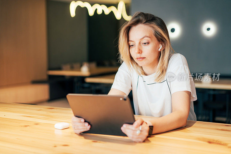 年轻的职业女性坐在现代办公空间里使用数字平板电脑。