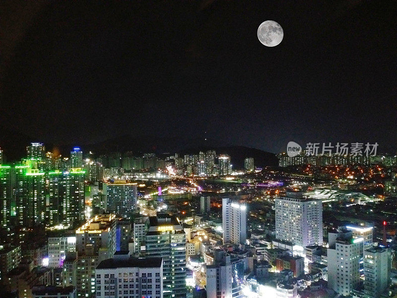 一个大城市的夜景与一轮圆月。