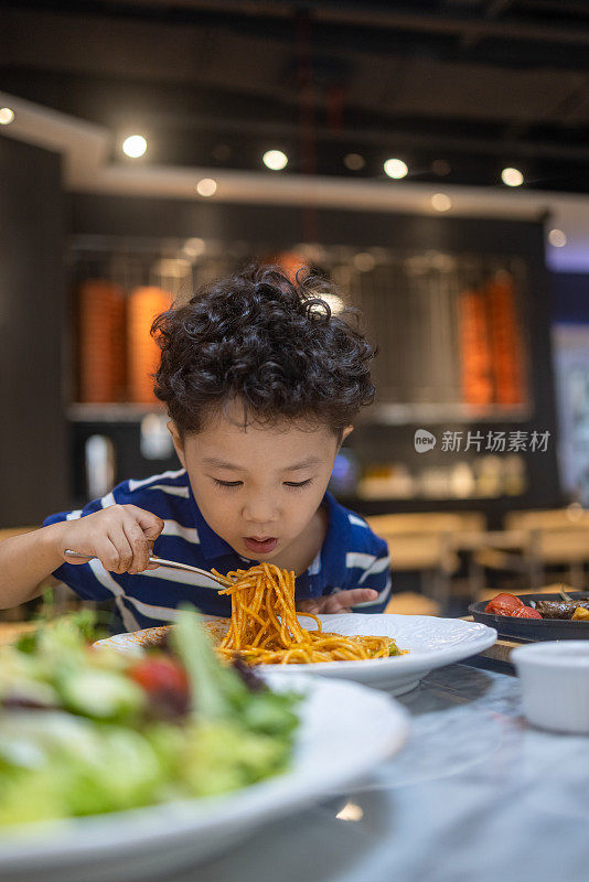 一个小男孩在餐馆里吃意大利面