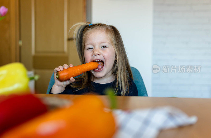 小女孩在厨房里吃胡萝卜