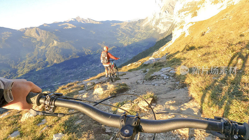 在阿尔卑斯山脉，一名男子推着山地自行车手沿着小路行进