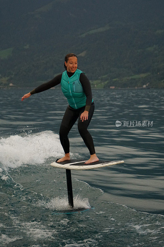 一名年轻女子在船后骑着水翼冲浪板