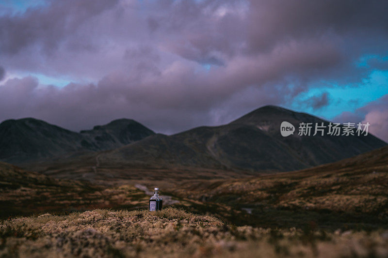 北方之旅。宁静的山景和引人注目的天空。一个瓶子掉在苔藓上