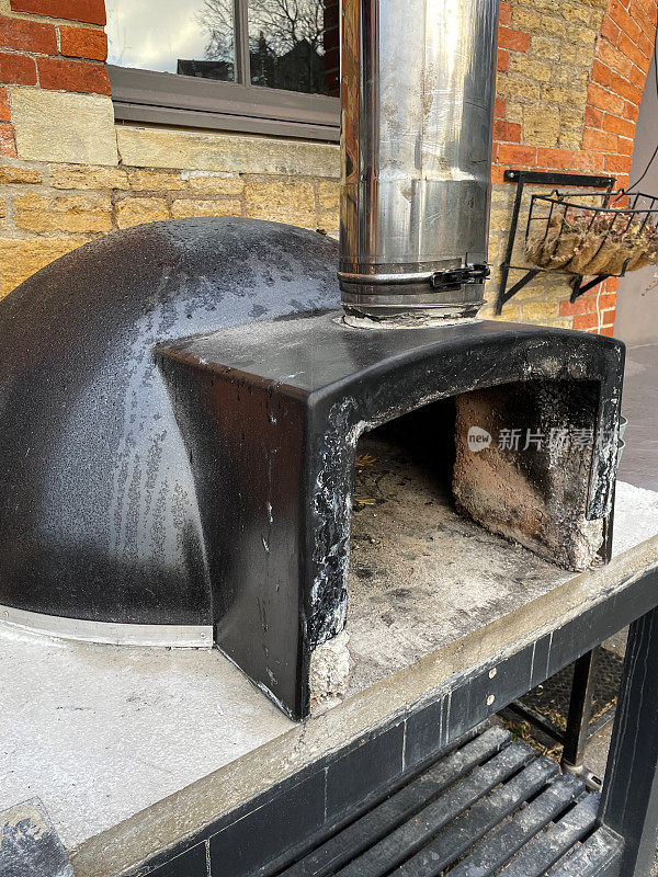 近距离拍摄的户外，不锈钢，石头基地披萨烤箱在一个砖墙花园