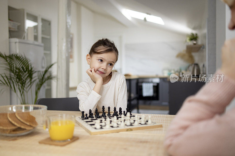 一个白人小女孩和她奶奶在家里下棋