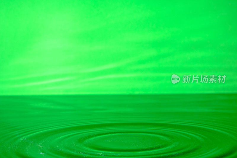 明亮的绿色背景与发散的圆圈从水滴表面的水。