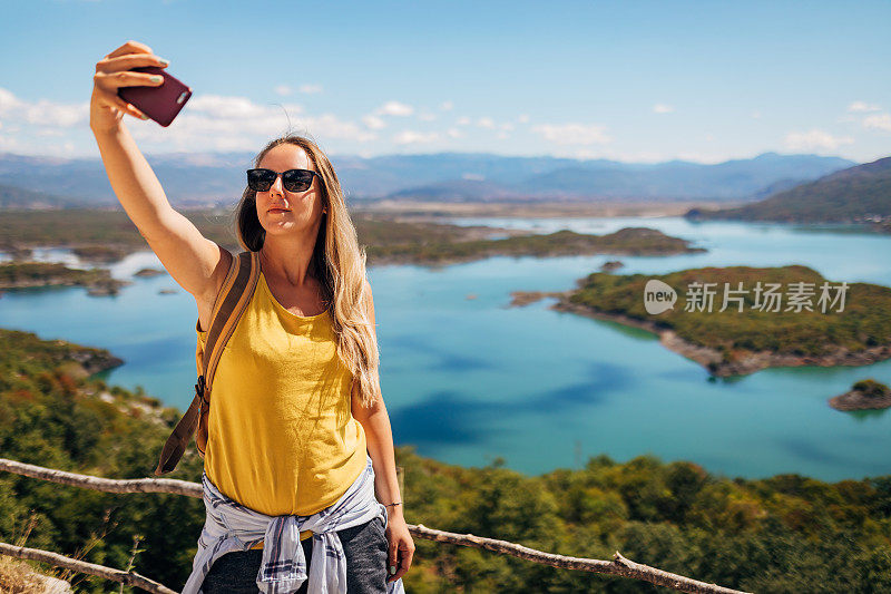 站在瞭望台上俯瞰冰川湖峡谷时，一位美丽的女子正在自拍。