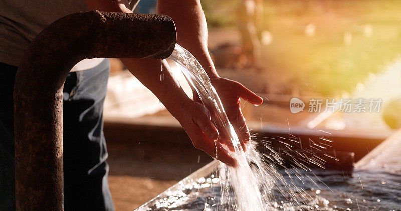 一名男子用从户外水管里流出的自来水洗手