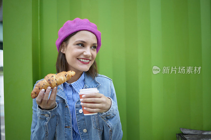 女人咬牛角面包户外酒吧早餐