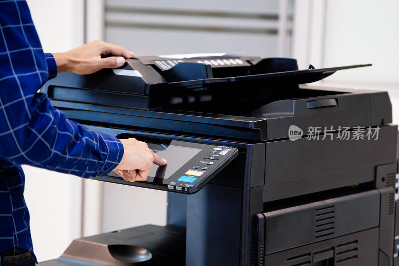 商务人士按下面板上的按钮，便可在办公室内使用影印机或打印机打印及扫描文件纸张。