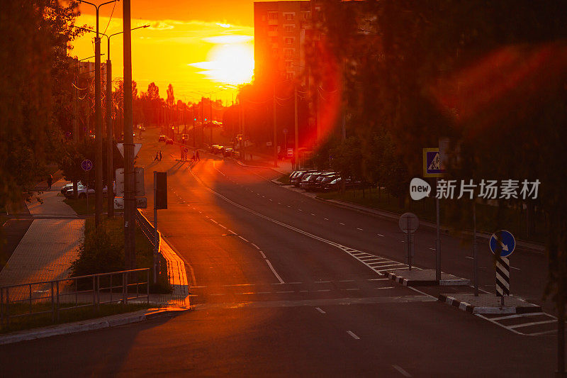 道路被夕阳照亮。城市街道的野花。晚上光线。镜头光晕。道路标记。日落