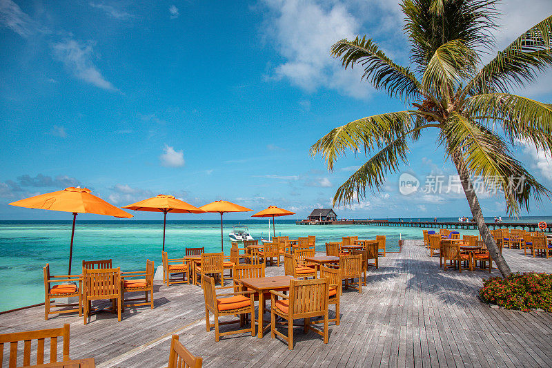 热带户外酒吧餐厅在海边的木甲板码头，有遮阳伞
