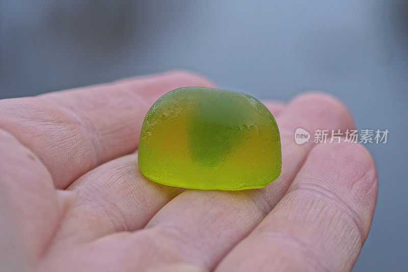 一个小的绿色糖果果酱糖放在手上的手指上