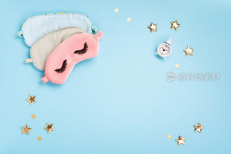 睡眠面具，金色星星和闹钟在蓝色背景。世界睡眠日概念。