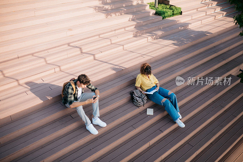两个学生课后坐在城市户外的楼梯上