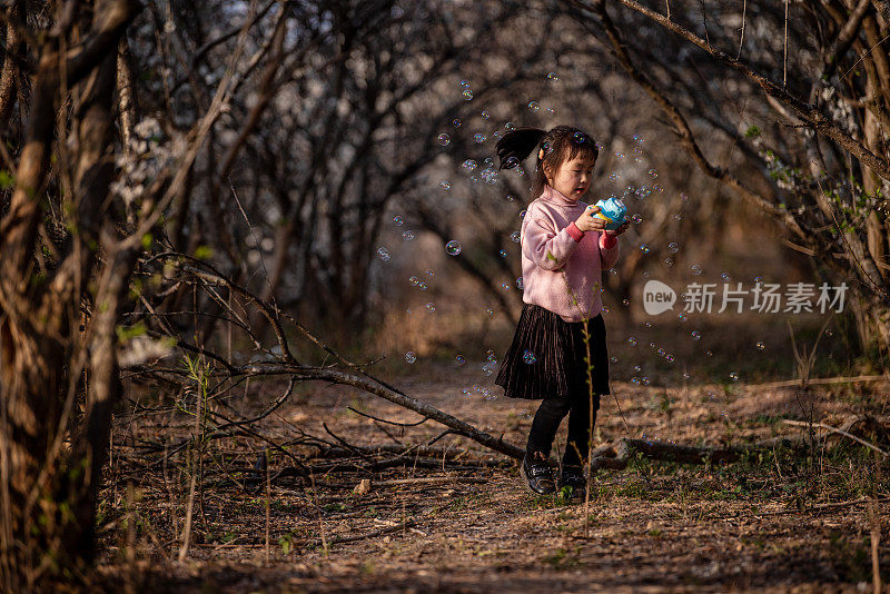 一个小女孩在森林里用吹泡泡机吹泡泡