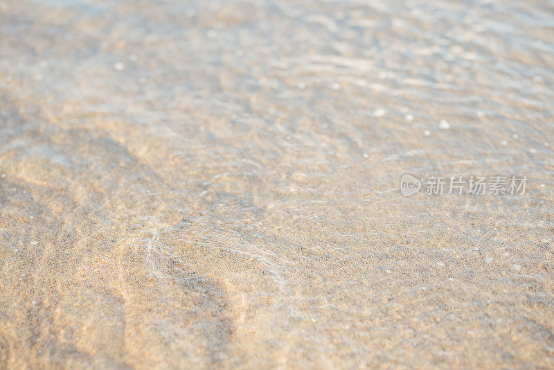 潮水退去后，夏季海滩上沙子纹理的特写照片。