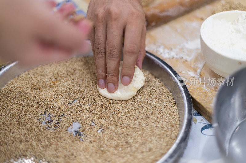 中国面食制作:中国芝麻面包。女人揉面团。制造碳水化合物食物的过程。