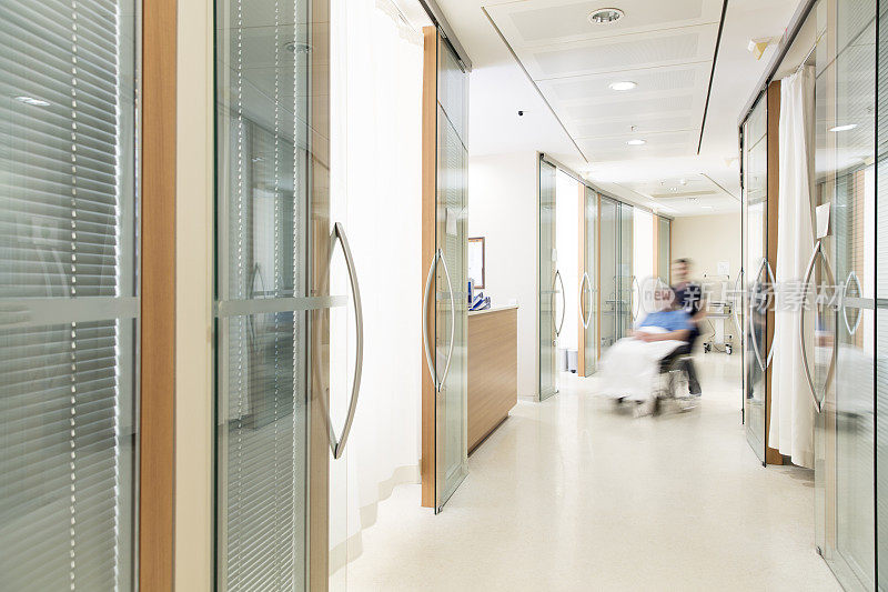 护士用轮椅抱着病人。现代化的医院走廊。