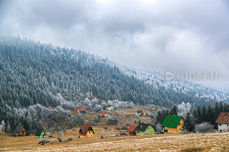 美丽的风景在山上，村庄在冬天多云的天空下