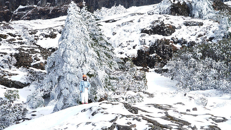 一个女人在寒冷的天气里穿行于白雪覆盖的山林之中