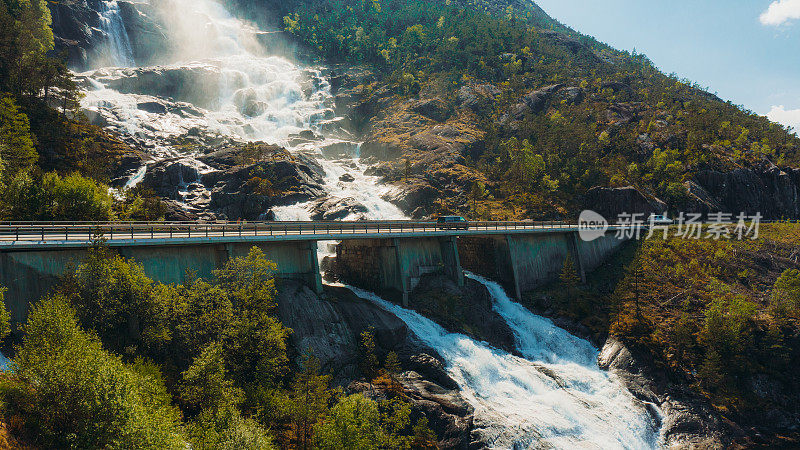 鸟瞰露营车在挪威风景优美的瀑布上行驶的田园诗般的山路