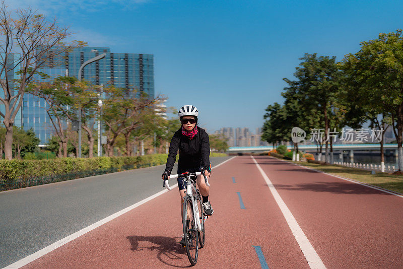 在城市公园路上骑公路自行车的女人